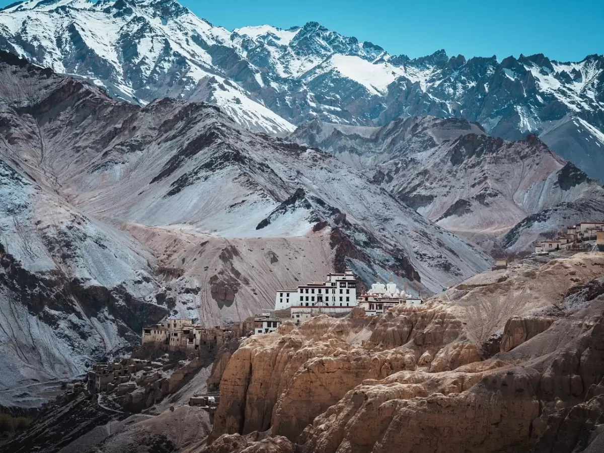 Lamayuru Monastery Ladakh stunning view with white gompa on moonland cliffs against snow-capped Himalayan peaks under clear blue sky, iconic attraction on Leh Kargil highway in Ladakh tour packages