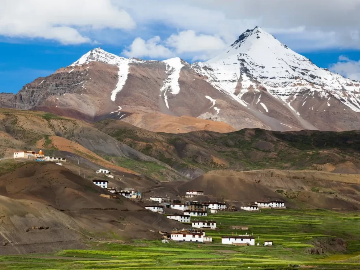 Langza Village near Kaza during partly cloudy skies, featuring white monasteries prayer flags Chowri Kangri peak villages, perfect cultural experience Himachal tour package.