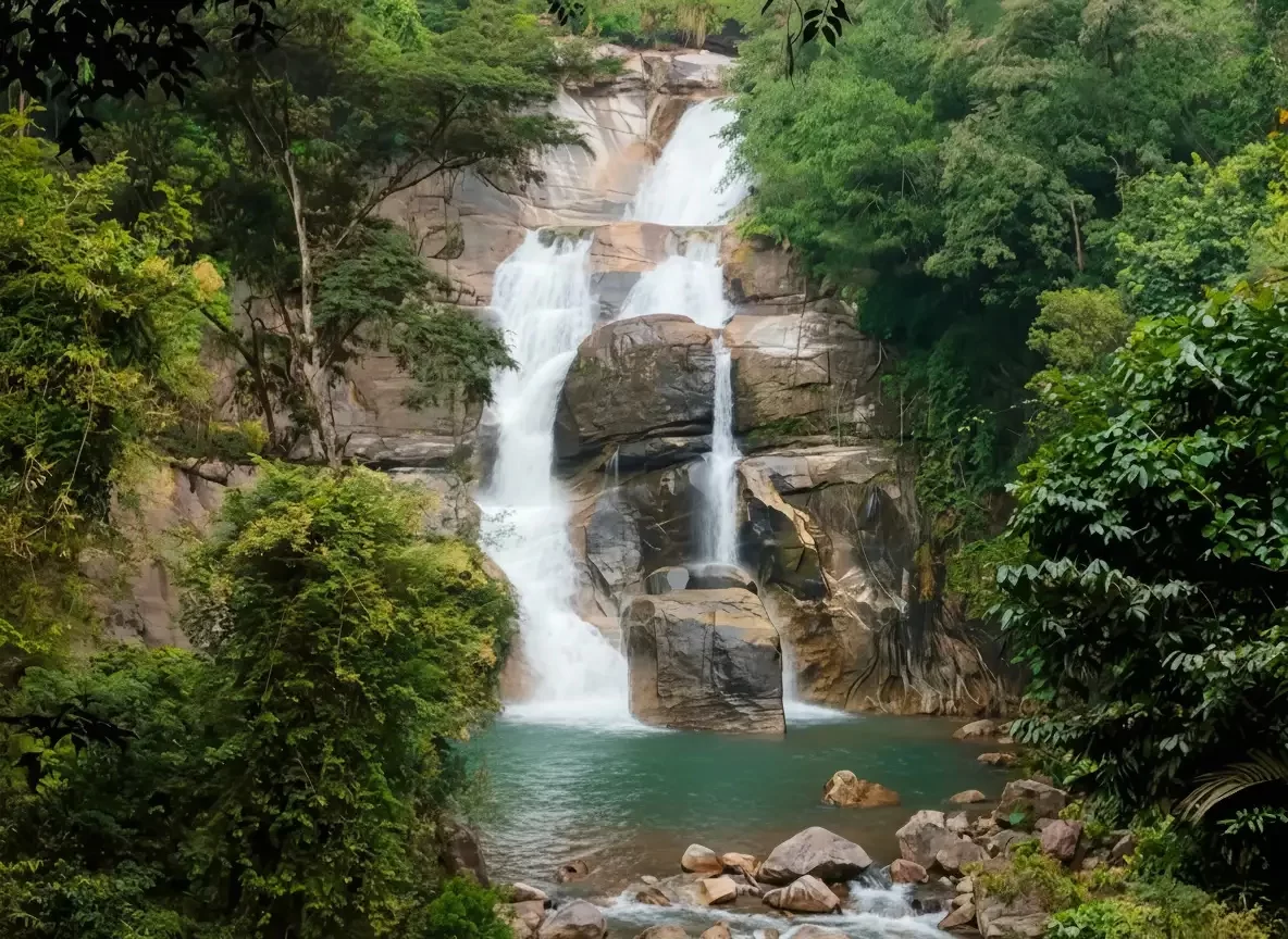 Laws Falls Cascading multi-tier waterfall at Laws Falls, Coonoor, surrounded by lush tropical rainforest and rocks.