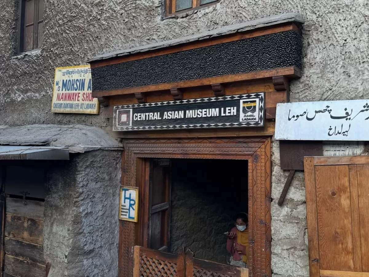 Central Asian Museum entrance in Leh Market with multilingual signboards and Moravian Mission Shop nearby, showcasing Silk Road heritage, perfect India tour package.