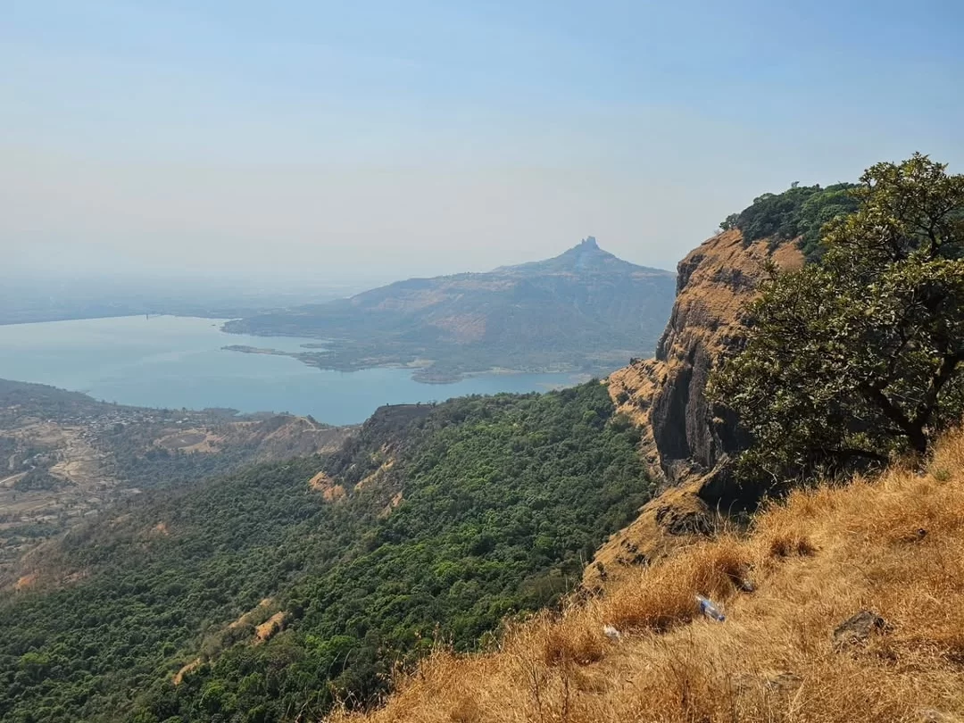View from Little Chowk Point in Matheran, Maharashtra, overlooking lush valleys, rocky cliffs, and a distant lake, a scenic viewpoint featured in Maharashtra tour packages.
