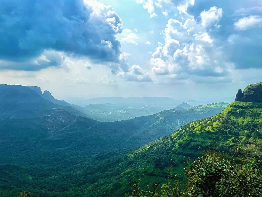 Panoramic valley view from Lords Point in Matheran, Maharashtra, showcasing lush green hills and dramatic cloud-filled skies, a scenic viewpoint featured in Maharashtra tour packages.
