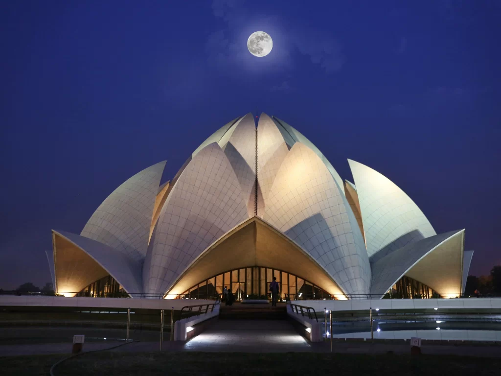 Lotus Temple, New Delhi – illuminated Bahá’í House of Worship under a full moon, stunning white marble lotus petals glowing at night, perfect spiritual highlight for Delhi city tour packages.