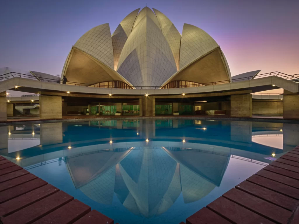 Lotus Temple, New Delhi – twilight view of illuminated white marble lotus petals perfectly reflected in the tranquil pool, iconic Bahá’í House of Worship and serene highlight of Delhi city tour packag