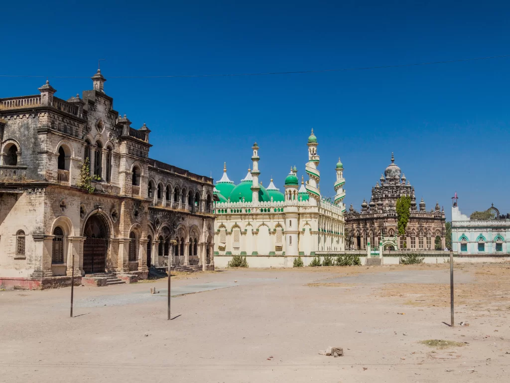 Mahabat Maqbara complex Junagadh featuring Bahauddin Maqbara Jama Masjid with green onion domes minarets against blue skies, Indo-Islamic Gothic heritage perfect for Gujarat tour packages.