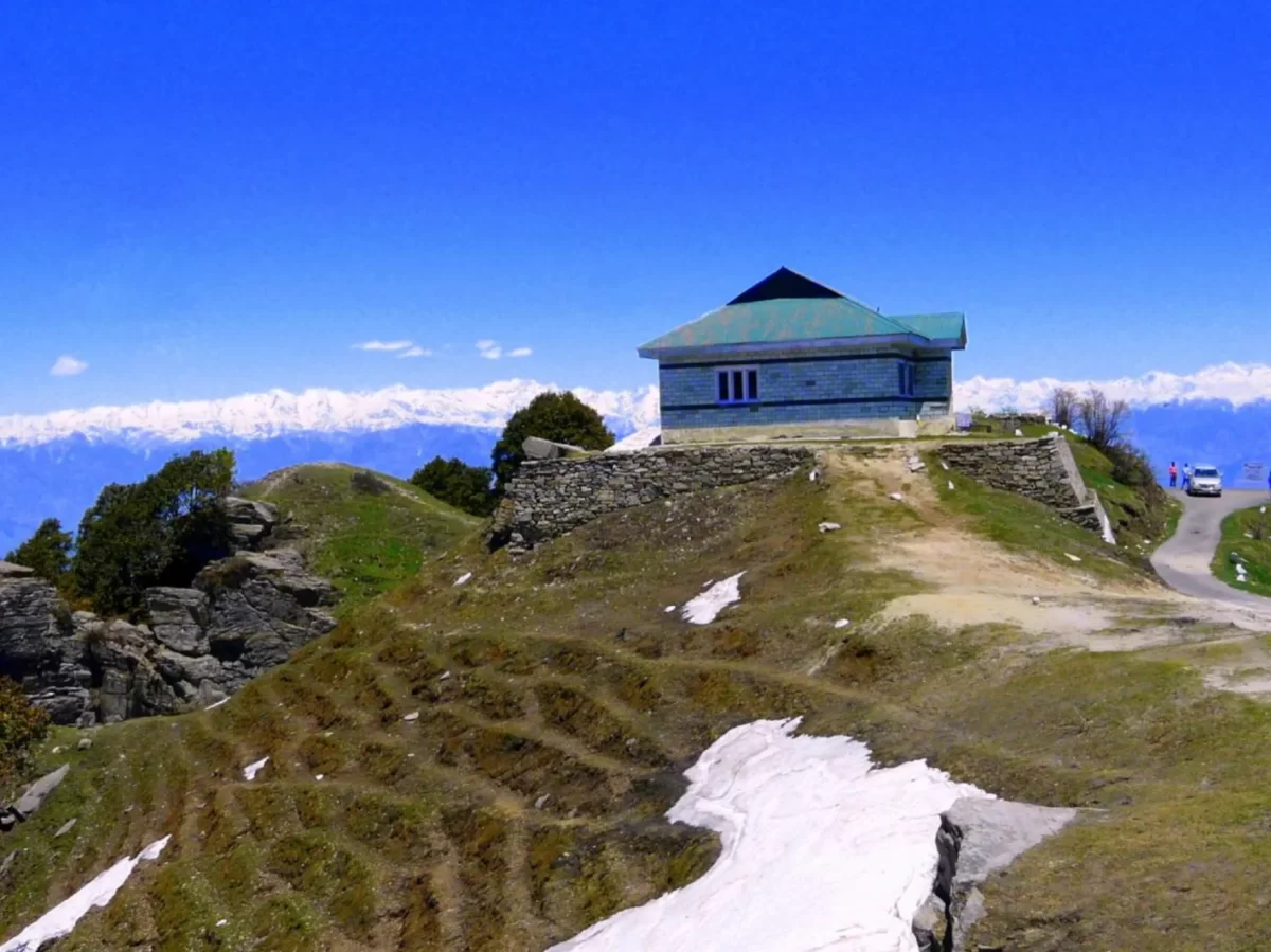 Observatory at Mahasu Peak Dalhousie during clear sky, featuring snow-capped Dhauladhar mountains, rocky hills, perfect adventure Himachal Pradesh tour package.