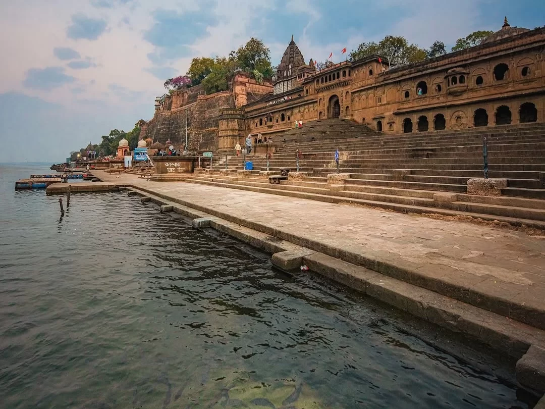 Stone ghats and temple architecture along the Narmada River in Maheshwar, Madhya Pradesh, showcasing historic fort walls and riverside steps, a cultural highlight featured in Madhya Pradesh tour packages
