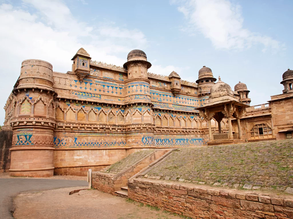 Man Mandir Palace at Gwalior Fort under clear skies, featuring intricate blue tilework and carvings, perfect heritage experience with Madhya Pradesh tour packages.