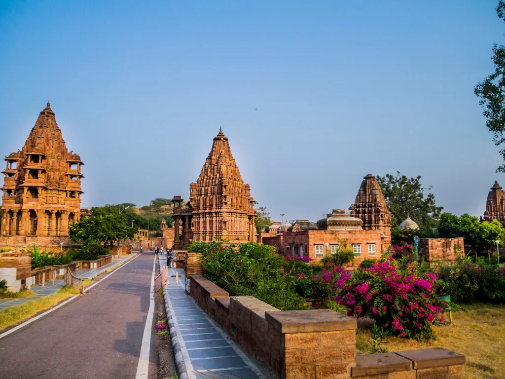 Mandore Garden at Jodhpur during golden hour, featuring red sandstone shikharas, cenotaphs, pathways, bougainvillea, perfect heritage experience Rajasthan tour packages.