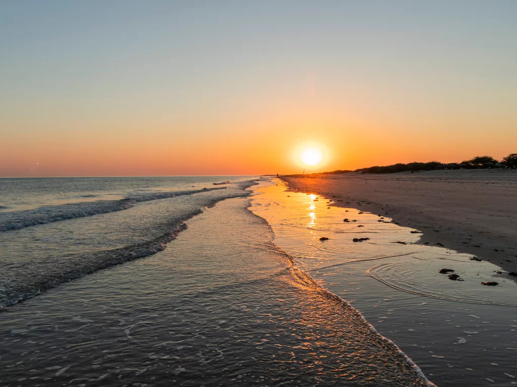 Mandvi Beach sunset at Kutch Gujarat during golden hour, featuring glowing sun, orange-pink skies, golden sea waves and sandy shoreline, perfect romantic experience with Gujarat tour packages.