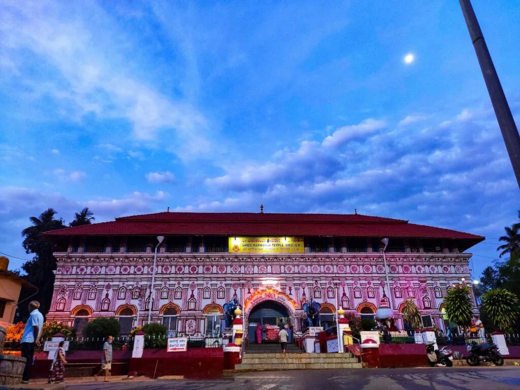 Shri Marikamba Temple in Sirsi during evening, featuring illuminated temple façade and dramatic clouds, perfect spiritual experience, Karnataka tour packages.