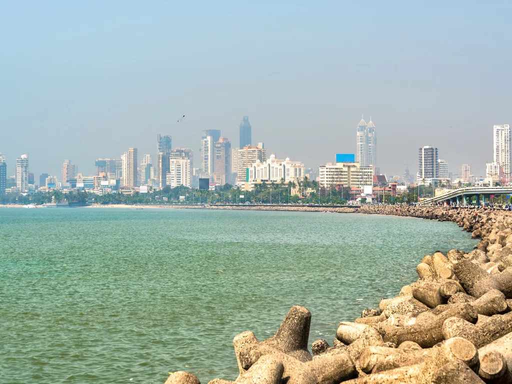 Marine Drive Mumbai skyline Arabian Sea tetrapods foreground hazy blue sky curving promenade urban skyline, perfect South Mumbai walking tour sunset photography package
