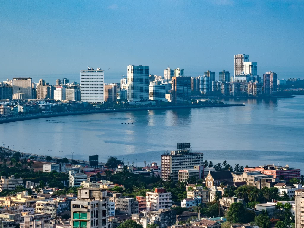 Marine Drive Mumbai elevated aerial view skyscrapers Arabian Sea curving promenade blue sky urban skyline, perfect South Mumbai walking tour sunset photography package. 