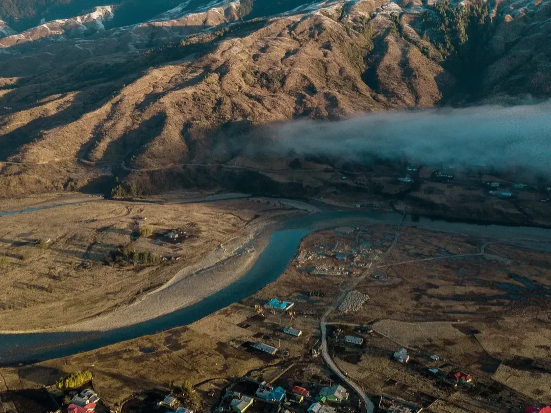 Mechuka View Point breathtaking aerial landscape of winding river and rugged mountains under misty skies in Arunachal Pradesh Package.