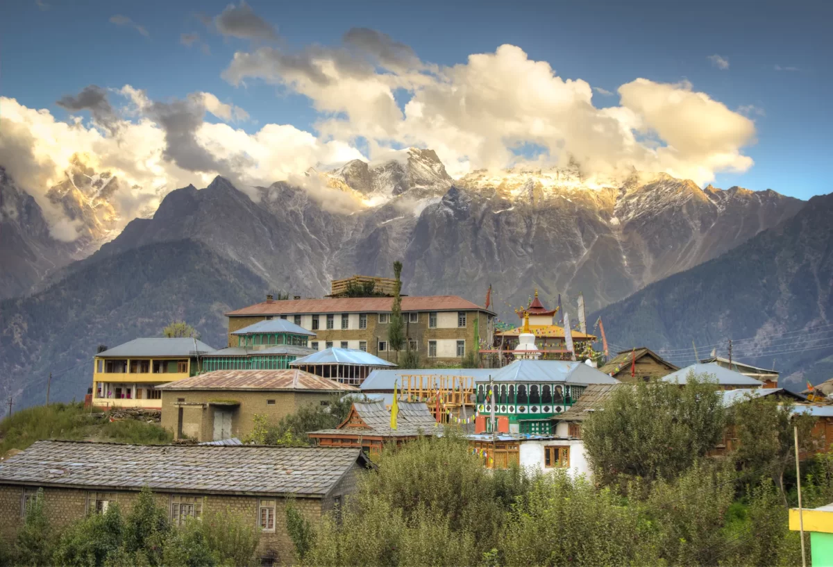Hu-Bu-Lan-Kar Monastery at Kalpa during partly cloudy skies, featuring chortens colorful buildings snowy Kailash peaks trees, perfect spiritual experience Himachal tour package.