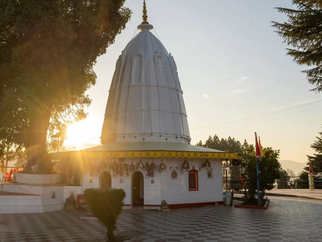Mostamanu Temple in Pithoragarh, Uttarakhand with its white domed structure glowing at sunset, a scenic hilltop shrine included in Uttarakhand tour packages