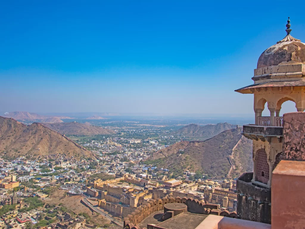 Panoramic Jaipur city view from Nahargarh Sunset Point during clear day, featuring Aravalli hills and Amber Fort, perfect romantic experience Rajasthan tour packages.