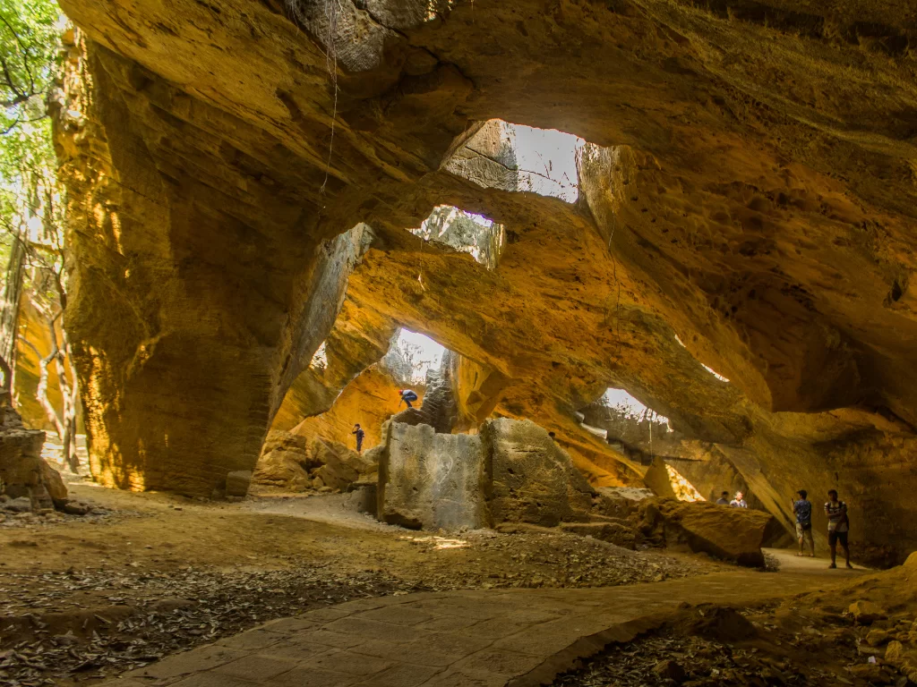 Exploring Naida Caves at Diu during golden hour sunlight, featuring dramatic rock arches and tunnels, perfect adventure experience Diu tour package.