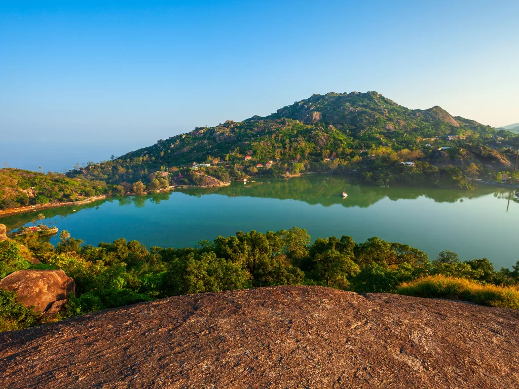 Nakki Lake Mount Abu elevated vista, featuring turquoise lake boats green forested hills town Nakki Lake reflections blue skies morning light, perfect Rajasthan tour packages. ​ ​