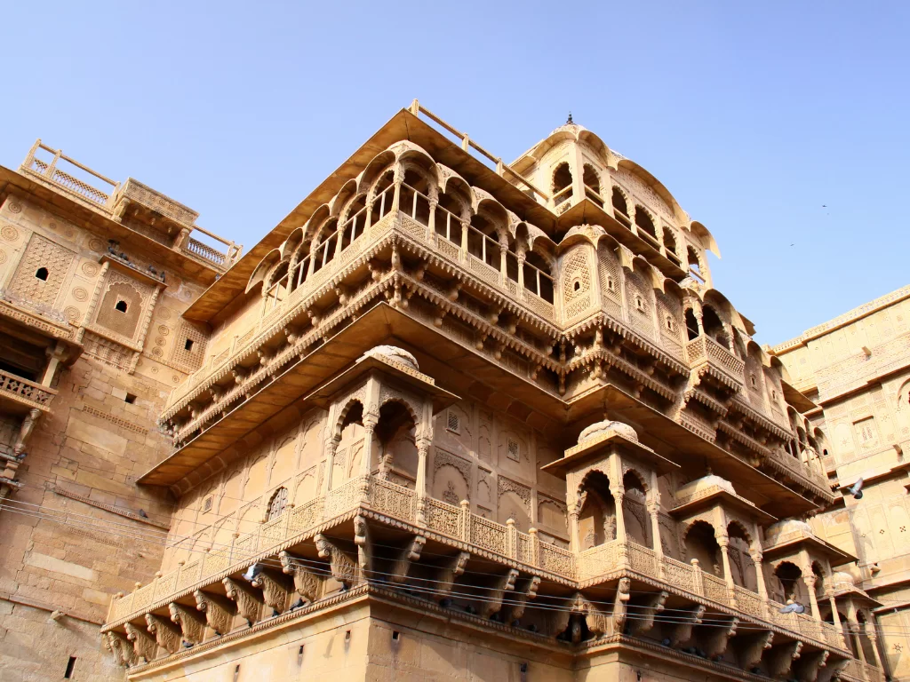 Nathmal Ki Haveli Jaisalmer multi-level sandstone structure jharokhas domes carved balconies blue sky featured in Rajasthan tour packages