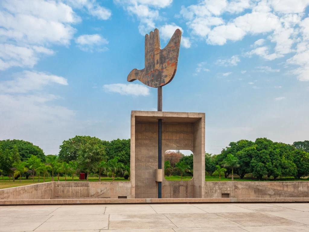 Iconic Open Hand Monument at Chandigarh during clear sky, featuring palm bird sculpture, concrete base, palm trees, perfect cultural Chandigarh tour package.