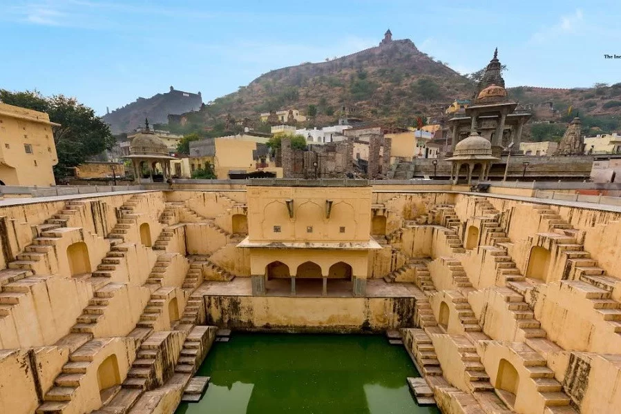 Panna Meena Ka Kund Jaipur Rajasthan wide stepwell green water pool yellow sandstone stairs Amer Fort hill background Rajasthan tour packages.