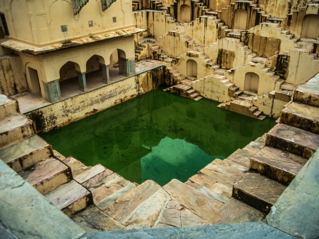 Panna Meena Ka Kund Jaipur Rajasthan historic stepwell crisscross sandstone stairs green water pool arches Rajasthan tour packages.