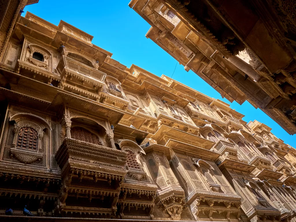 Patwon Ki Haveli Jaisalmer low angle view sandstone balconies jharokhas intricate carvings blue sky featured in Rajasthan tour packages