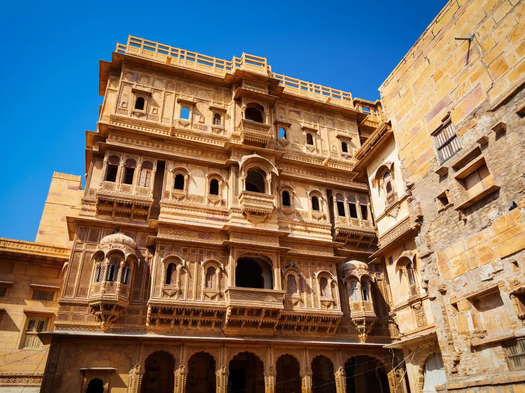 Patwon Ki Haveli Jaisalmer multi-storey sandstone haveli jharokhas balconies carved facades blue sky featured in Rajasthan tour packages