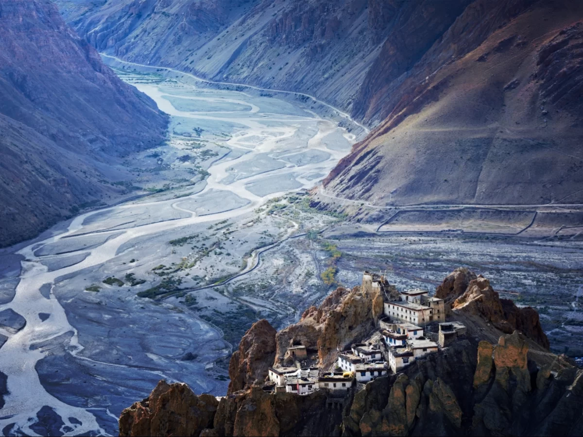 Key Monastery near Kaza Pin Valley winter vista, featuring ancient white monastery perched rocky cliff overlooking Spiti River valley snow peaks dramatic skies, perfect Himachal Pradesh tour packages.