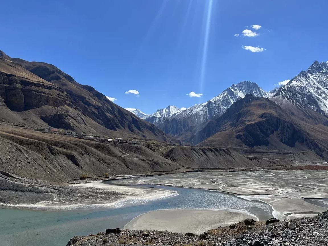 Pin Valley National Park near Kaza during sunny skies, featuring Spiti river valley brown cliffs snow peaks green meadows, perfect adventure experience Himachal tour package.