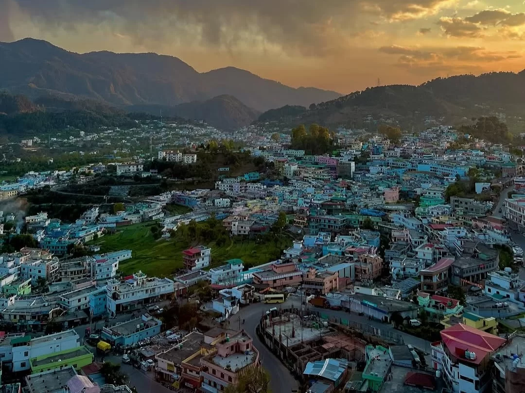 Pithoragarh city panoramic view with colorful houses and scenic hill landscape at sunset in Uttarakhand tour packages.