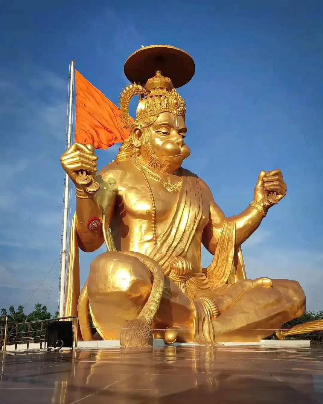 Golden Hanuman statue at Pitra Parvat Indore during clear daylight, featuring saffron flag meditative pose, perfect spiritual Madhya Pradesh tour package.