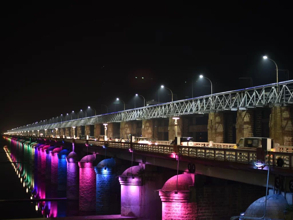 Prakasam Barrage at Vijayawada during night lighting, featuring colorful piers and reflections, perfect romantic experience Andhra Pradesh tour packages.
