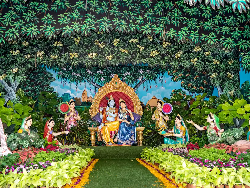 Radha Krishna tableau at Prem Mandir during festival, featuring central deities on throne, gopis with melons, Vrindavan forest backdrop, perfect spiritual experience with Mathura Vrindavan tour package.