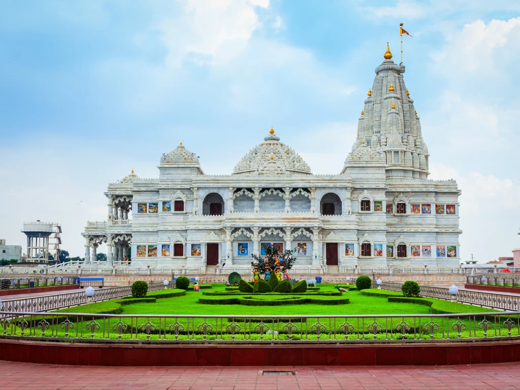 Prem Mandir at Vrindavan during clear daytime, featuring white marble architecture, golden spires, landscaped gardens, perfect spiritual experience with Mathura Vrindavan tour package.
