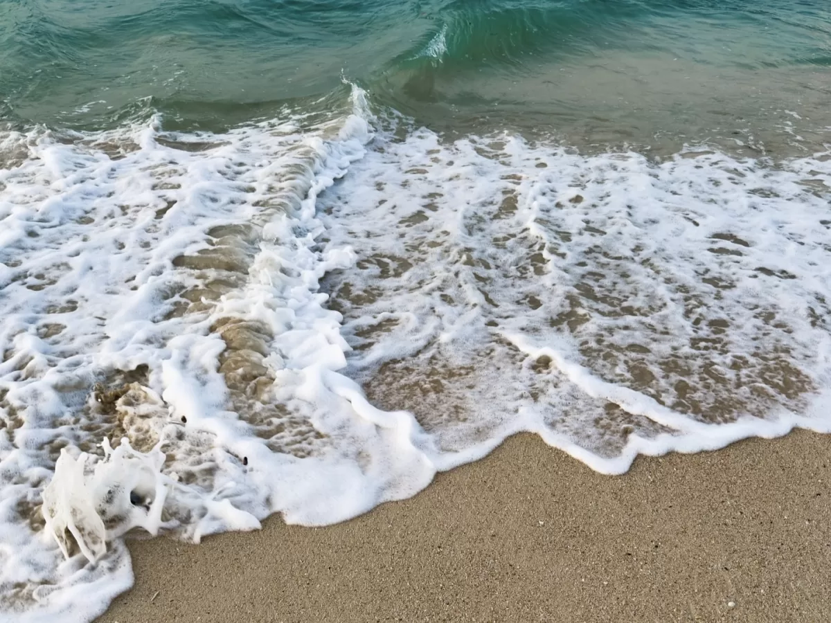 Radhanagar Beach No.7 Havelock Island Andaman golden hour panorama with scattered clouds, featuring turquoise waves crashing on rocky shoreline, perfect tropical beach adventure tour package. 