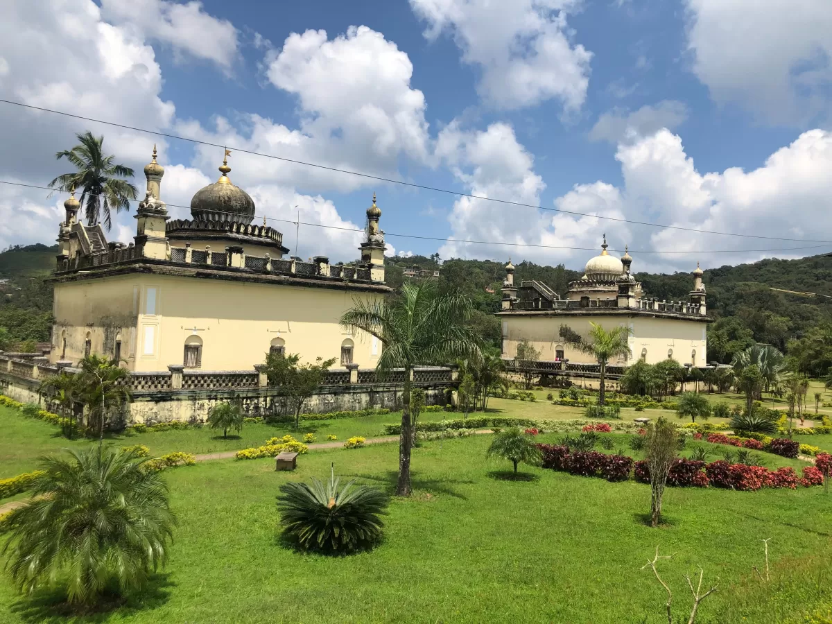 Raja's Tomb at Madikeri Coorg during partly cloudy day, featuring Indo-Saracenic domes, gardens, palms, flowers, hills, perfect cultural experience Karnataka tour packages.