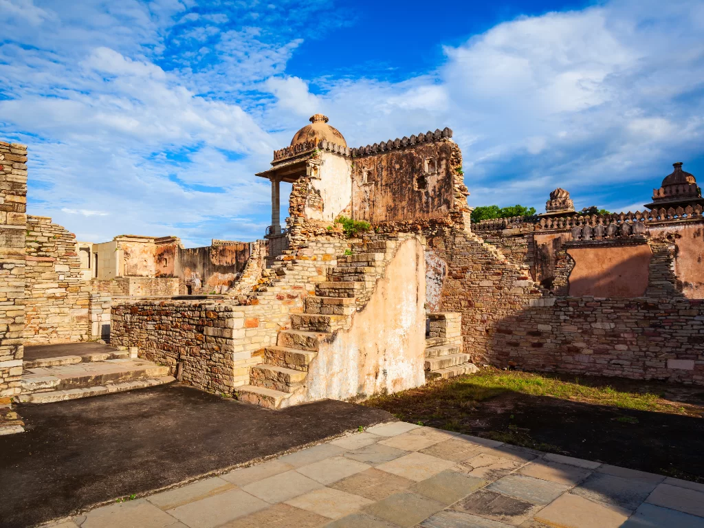 Side view of Rana Kumbha Palace ruins at Chittorgarh Fort in Rajasthan highlighting dome pavilion, stairs and weathered walls under partly cloudy sky, perfect Rajasthan tour package.