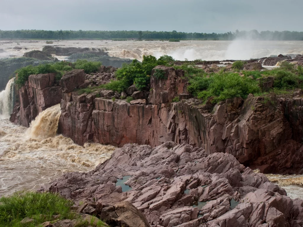 Raneh Falls near Khajuraho during monsoon season, featuring panoramic Ken River canyon multiple cascades granite cliffs vegetation, perfect Madhya Pradesh heritage nature tour package.
