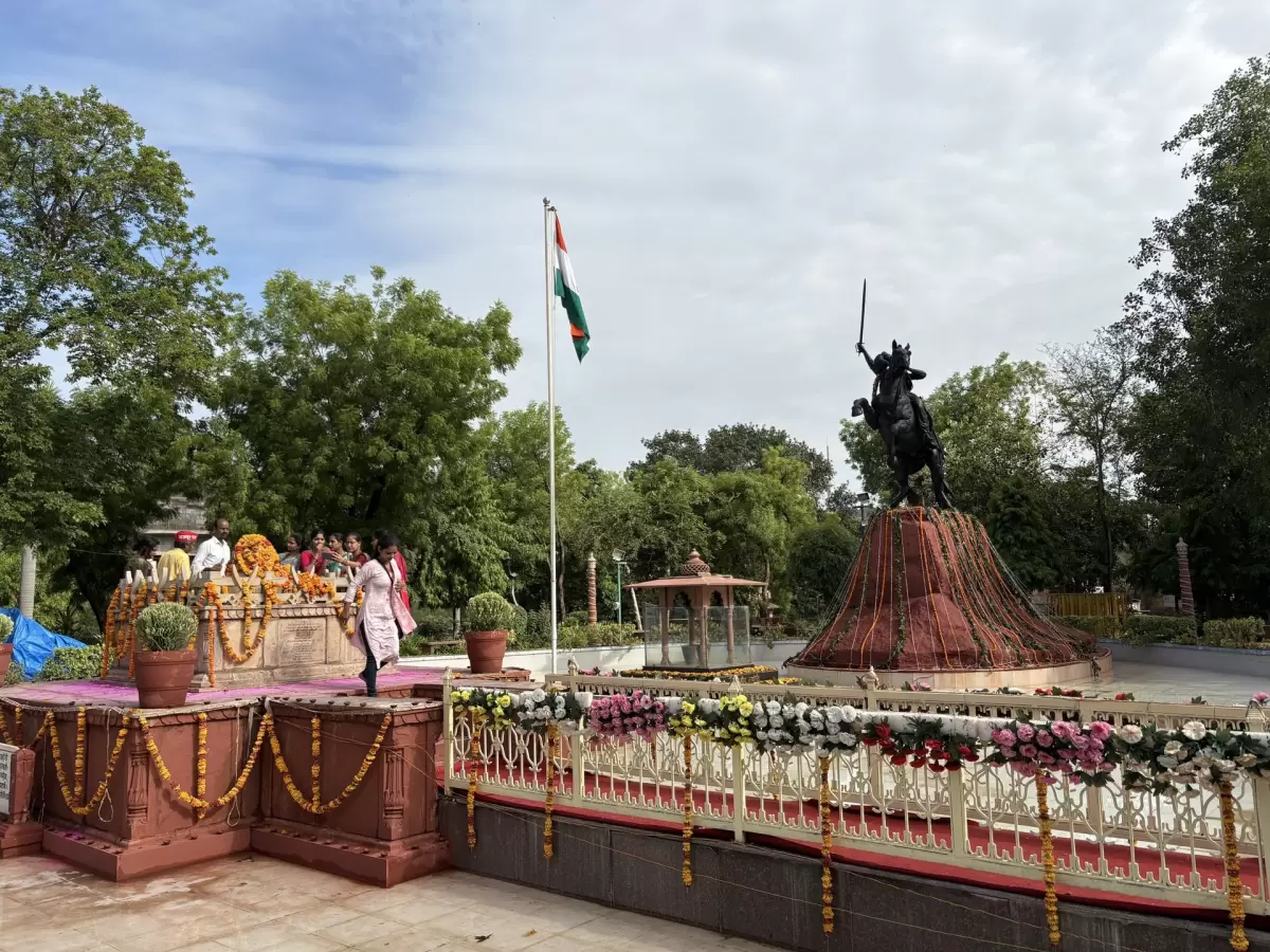 Rani Laxmibai Samadhi Sthal in Gwalior with decorated memorial platform, Indian flag, and equestrian statue of the queen, a historic landmark featured in Madhya Pradesh tour packages