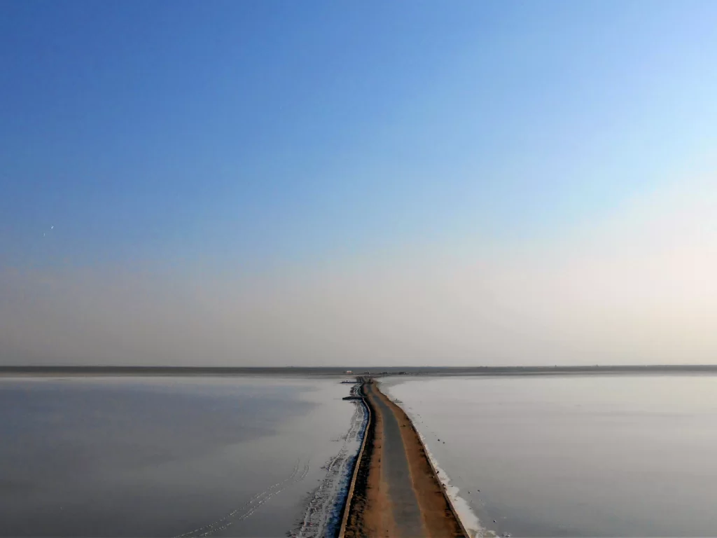 India Bridge road at Rann of Kutch during clear day, featuring endless salt desert horizon and vast white expanse, perfect adventure experience with Gujarat tour packages.
