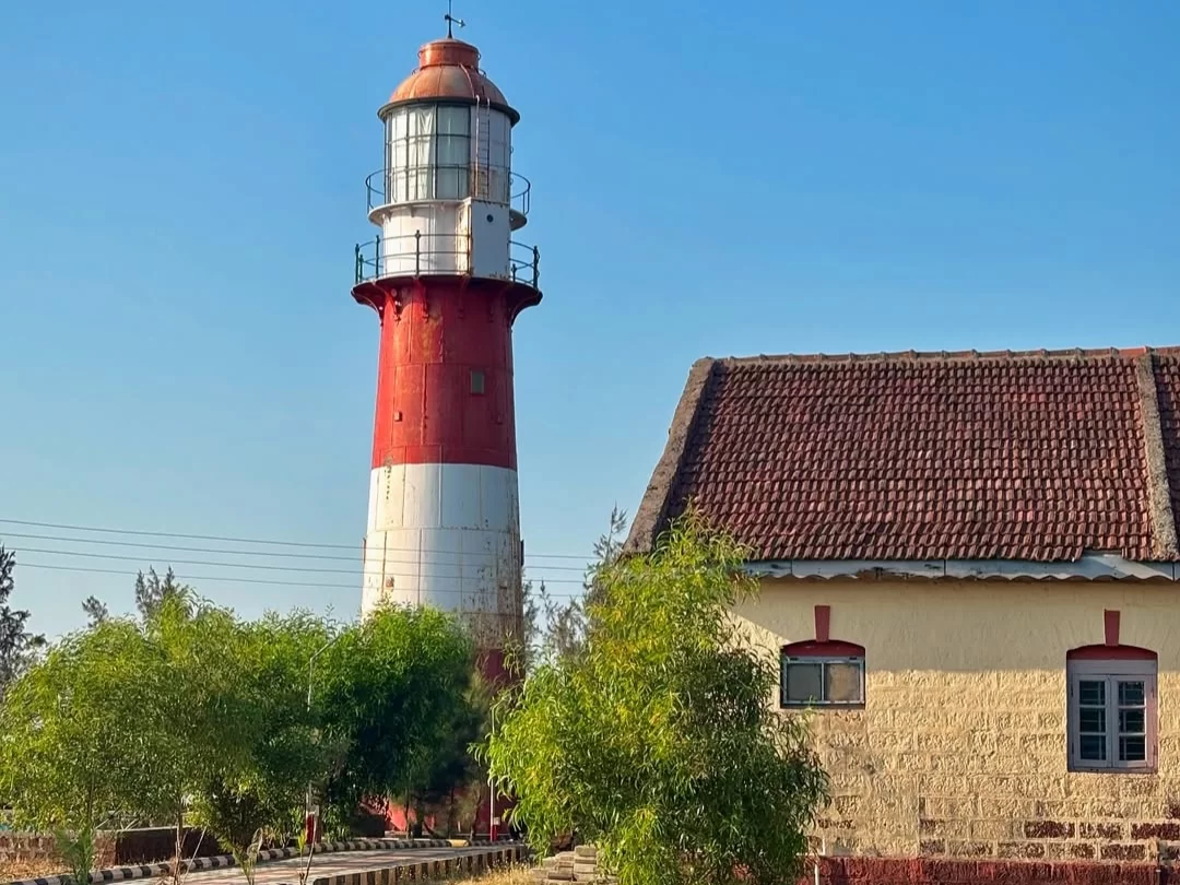 Ratnagiri Lighthouse in Maharashtra featuring the iconic red and white coastal tower beside traditional tiled-roof buildings and greenery, a scenic maritime landmark included in Maharashtra tour packages