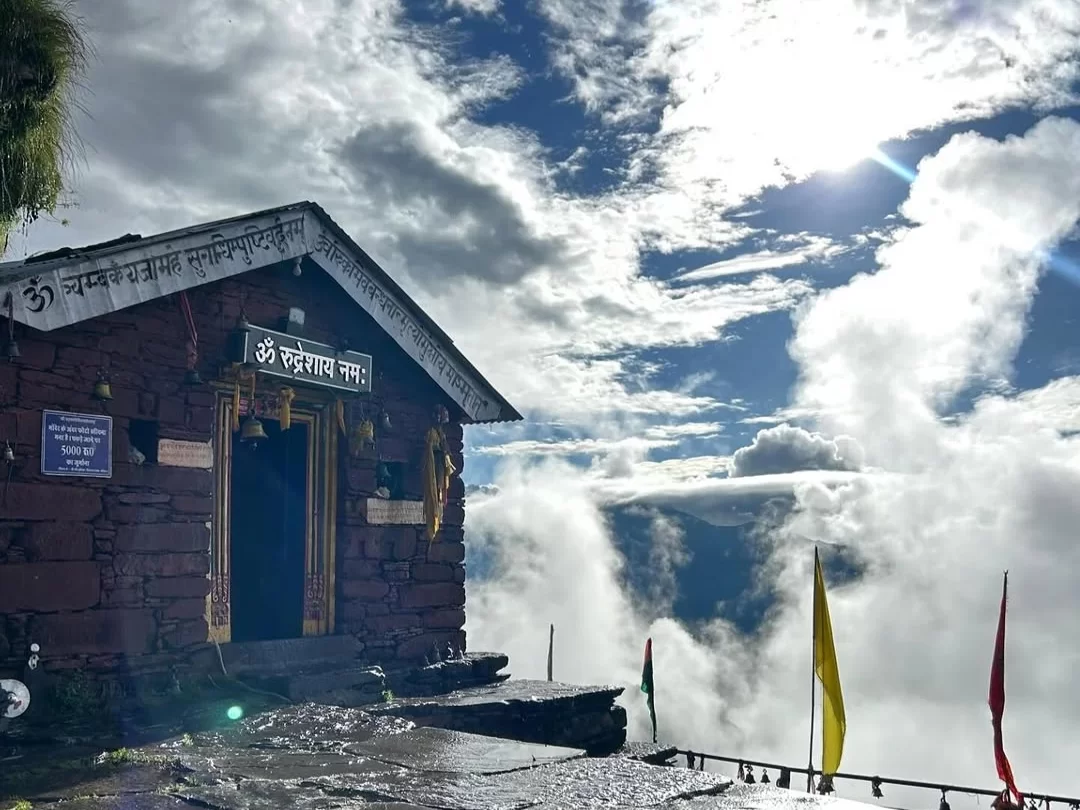 Rudranath Temple in Uttarakhand, perched above the clouds with colorful flags fluttering in the breeze—a divine and serene destination in Uttarakhand tour packages.