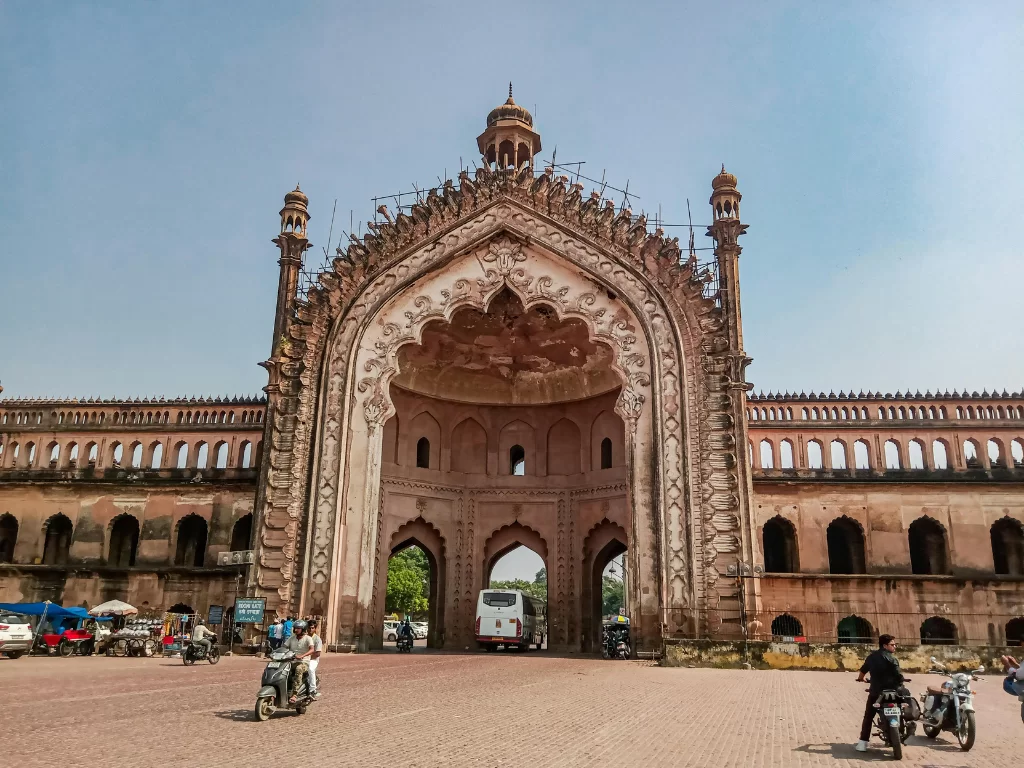 Rumi Darwaza under restoration at Lucknow during sunny day, featuring ornate arches vehicles plaza crowds, perfect cultural Uttar Pradesh tour package.