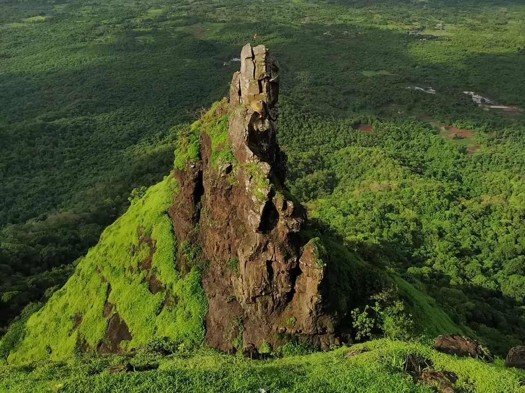 Dramatic rocky peak of Sagargad Fort near Alibaug, Maharashtra, surrounded by lush green hills and forested landscape, a trekking destination featured in Maharashtra tour packages.