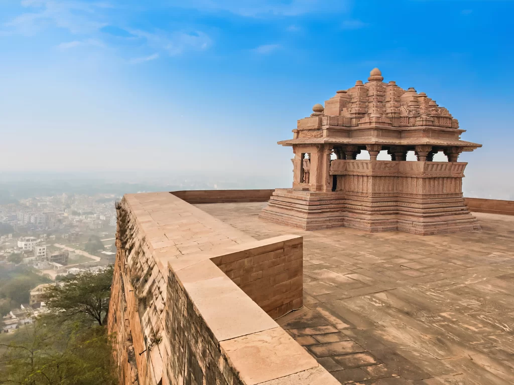 Sasbahu Temple at Gwalior Fort under hazy skies, featuring multi-domed pavilion and panoramic city views, perfect heritage experience with Madhya Pradesh tour packages.