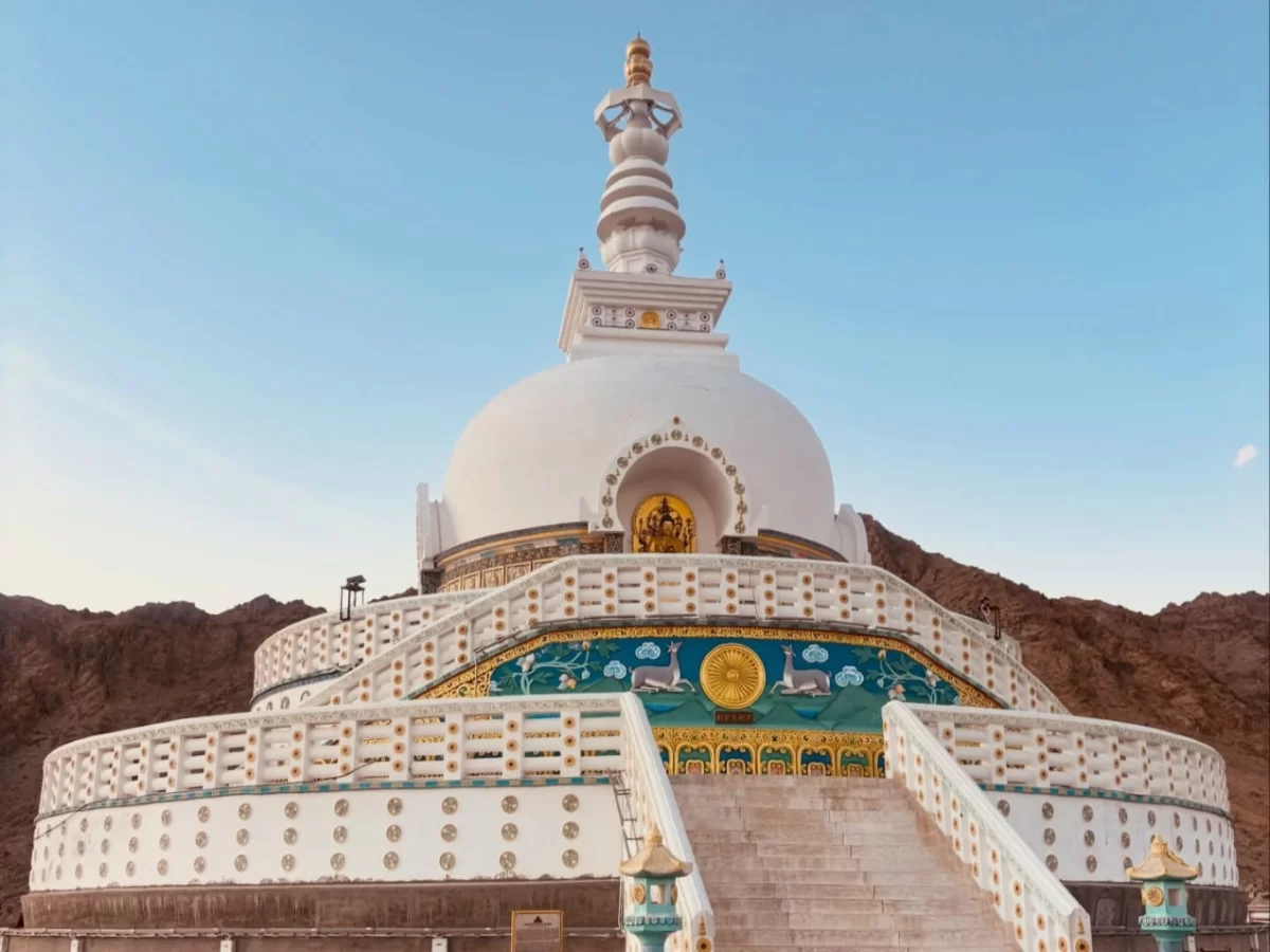 Shanti Stupa Leh Ladakh under clear blue sky, featuring pristine white stupa golden spire, turquoise golden murals stairs lamps, guardian figures, rugged brown mountain backdrop, perfect classic spiritual architectural experience with Leh Ladakh sightseei