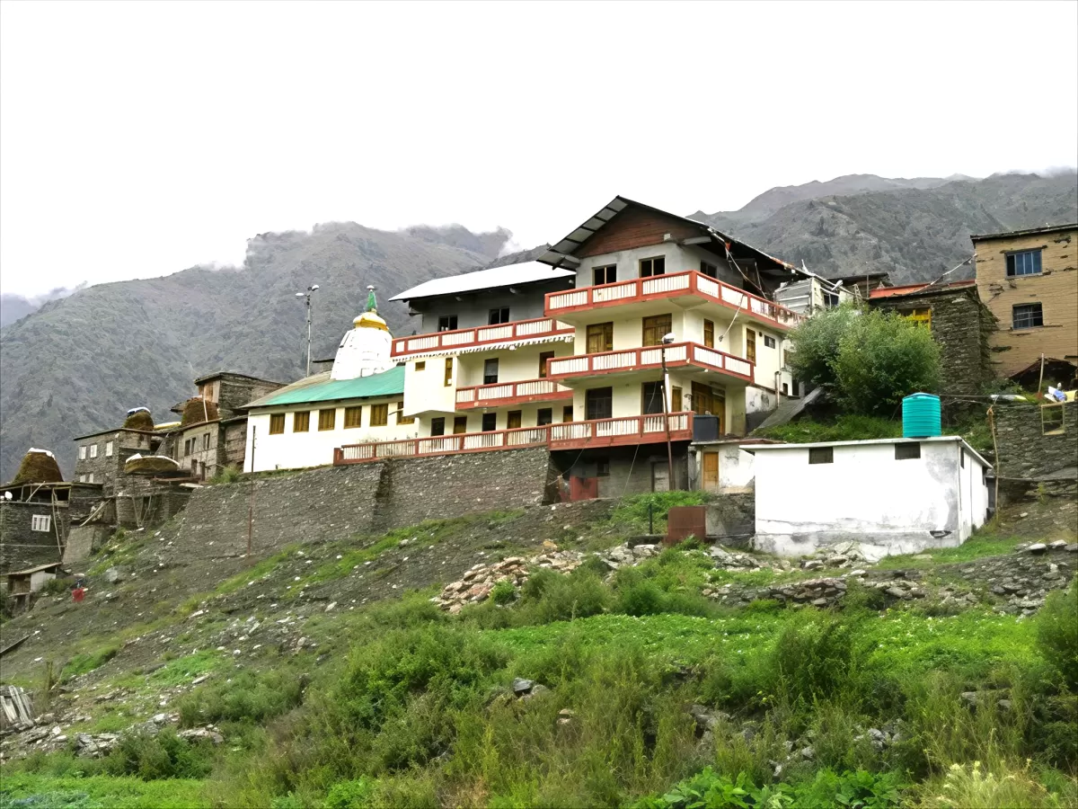 Shashur Monastery Keylong during overcast skies, featuring multi-story temple white dome green roof village homes stone wall mountains greenery, perfect spiritual experience Himachal Pradesh tour package.