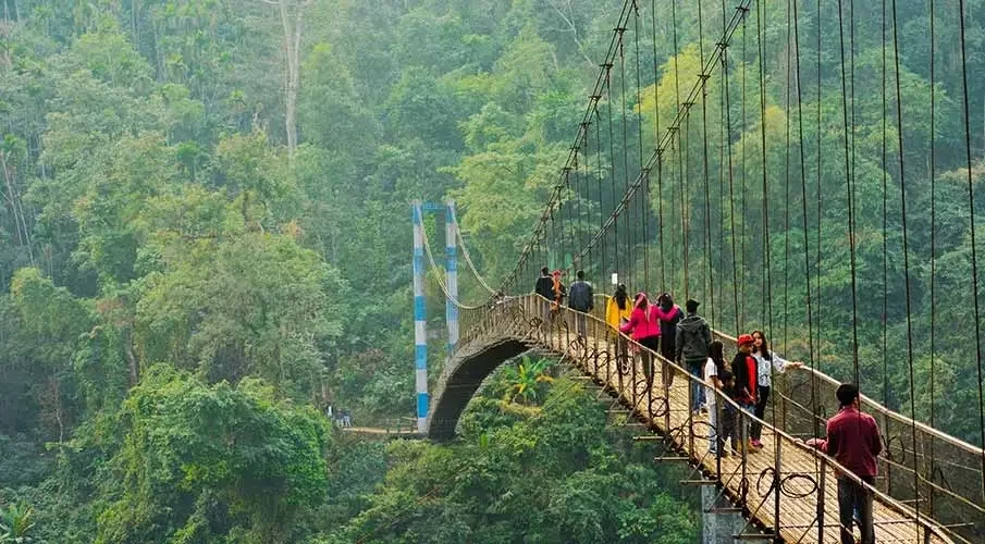 Shnongpdeng Suspension Bridge in Meghalaya, a scenic hanging bridge over the Umngot River surrounded by lush green hills and crystal-clear waters.